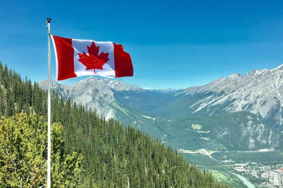 Imagem de uma bandeira do Canadá em frente a uma paisagem de tirar o fôlego para ilustrar conteúdo sobre as novas regras para intercâmbio no Canadá